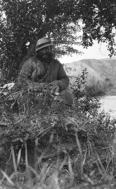 Chantos (Uighur) man sitting by Tekes river