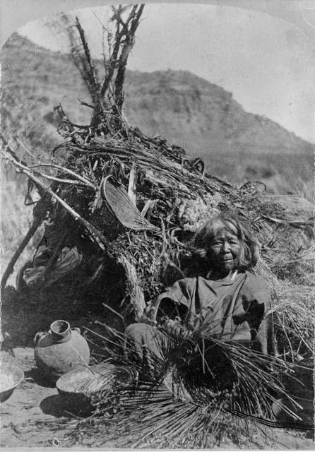 Basket maker sitting on ground weaving baskets