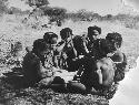 Group of boys and girls sitting close together, boys are making toy cars