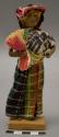 Doll, woman carrying colorful bundle of plant material