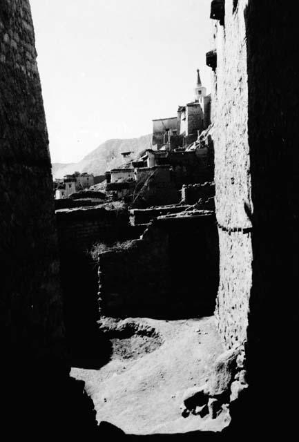 Town on a hillside seen through narrow space between buildings