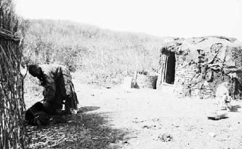 Old woman holding dog near dwellings