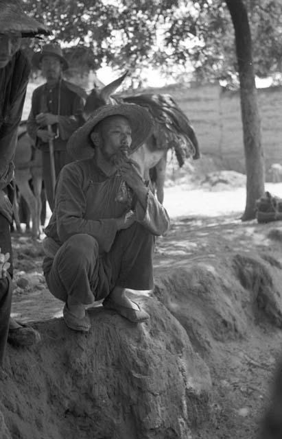 Man wearing a hat squatting at edge of ravine