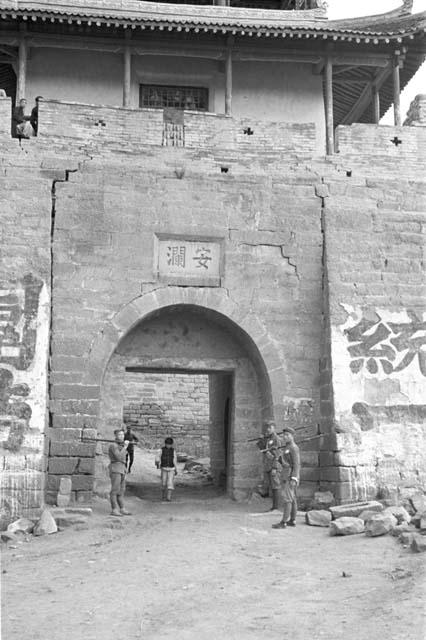 Several soldiers standing in front of large city gate