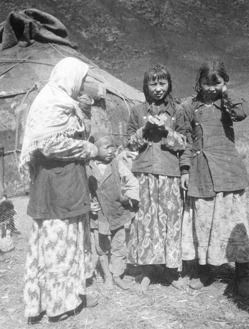 One woman, two girls, and one little boy in front of yurt