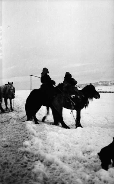 Two men on horses in the snow