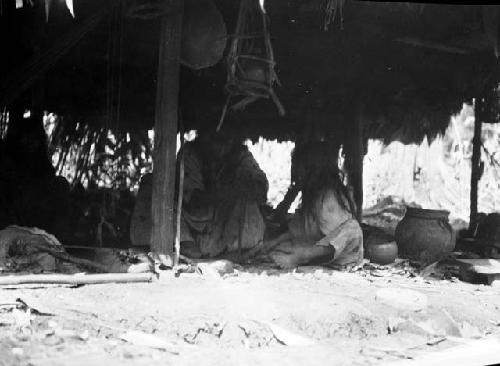 Native adult and child making a fire inside of dwelling