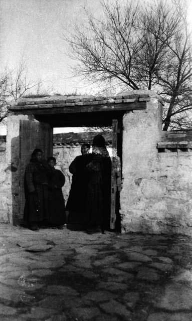 Three men and a boy standing in gateway in a wall