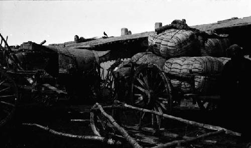 Man standing by cart piled full with large bundles