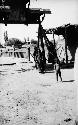 Three women and naked little boy standing by pailou and building by bridge