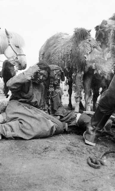 Two women seated, camels standing