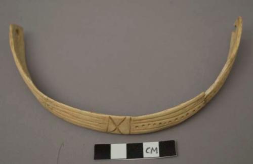 Bone ornament, 2 perforations, incised with 5 paralell lines, "IXI" shape and a