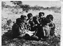 Group of boys and girls sitting close together, boys are making toy cars