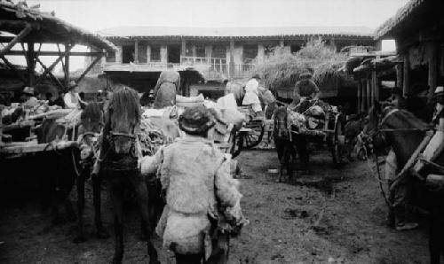 Open courtyard crowded with carts, horses and people