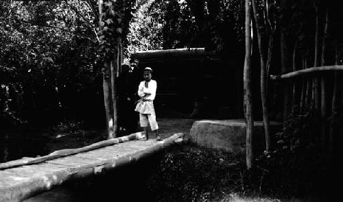 Boy and man at end of bridge in front of building set in trees