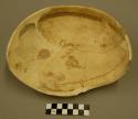 One half of a black on yellow pottery bowl - zoomorphic