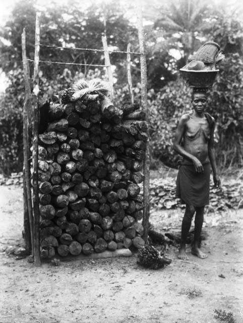 Woman next to pile of fire wood, Kirepo clan