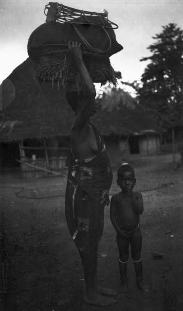 Woman carrying large load of rice on head, Sapo, Pudu clan