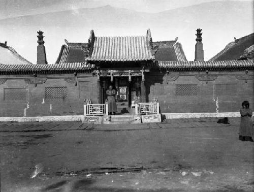 Man standing by entry, dog and child to one side