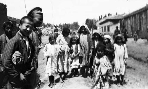 Chanto children, Uighur, standing in a street wearing head covering