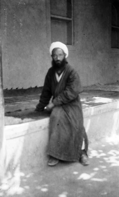 Old man with turban sitting on a carpeted platform