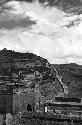 Buildings and walls built into hillside. Sign in front of largest building