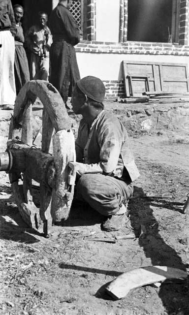 Carpenter mending wooden cartwheel