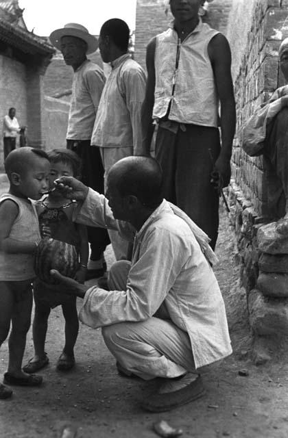 Yutaoho, Shansi, July 1935, man feeding melon to children