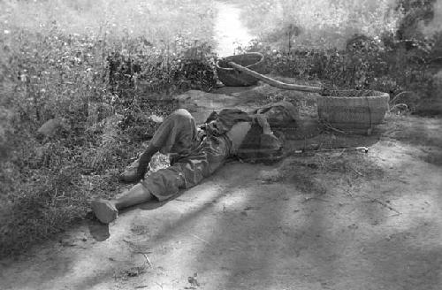 Basket-carrier asleep by road