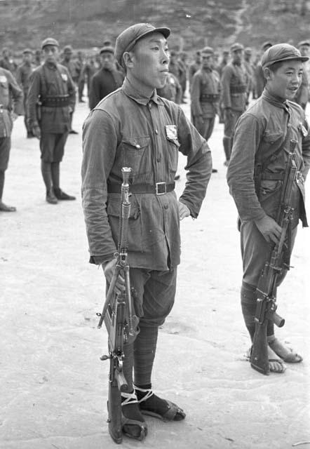 Portrait of soldier standing at attention. Other soldiers behind