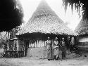 Head medicine woman and two other in front of medicine hut