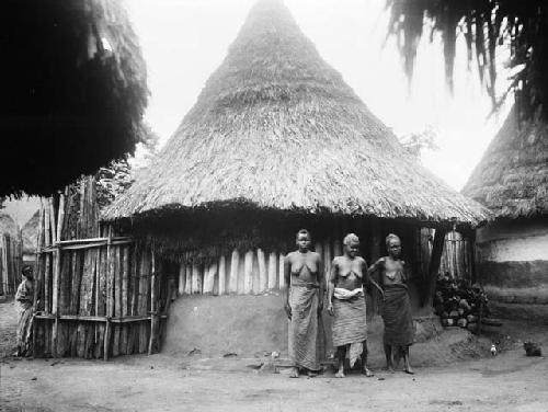 Head medicine woman and two other in front of medicine hut