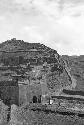 Buildings and walls built into hillside. Sign in front of largest building