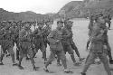 Group of soldiers marching, cliff visible in distance