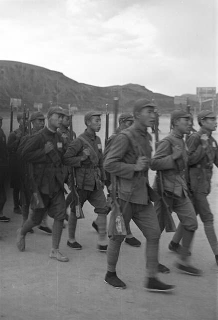 Group of soldiers marching, cliff visible in distance