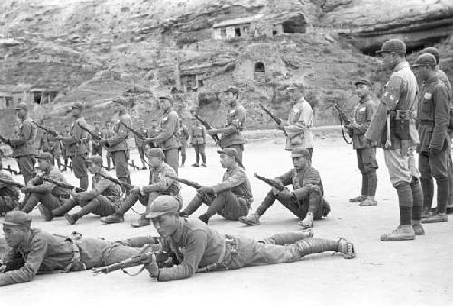 Three rows of soldiers in different stances during military drill