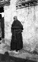 Portrait of monk standing in front of a wall