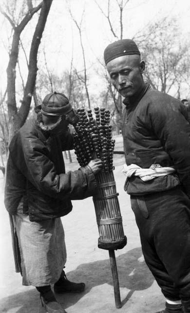 Man selling sugar-coated crab apples skewered on long sticks