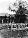 Several men with water buckets standing in front of buildings, ice on ground