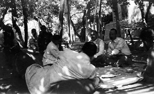 Grape Valley picnic, men reclining and sitting under trellised awning