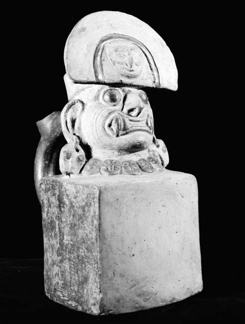 Stirrup vessel (spout missing), human head on cube with fangs