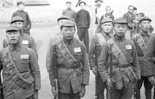 Two rows of soldiers, several men standing behind them