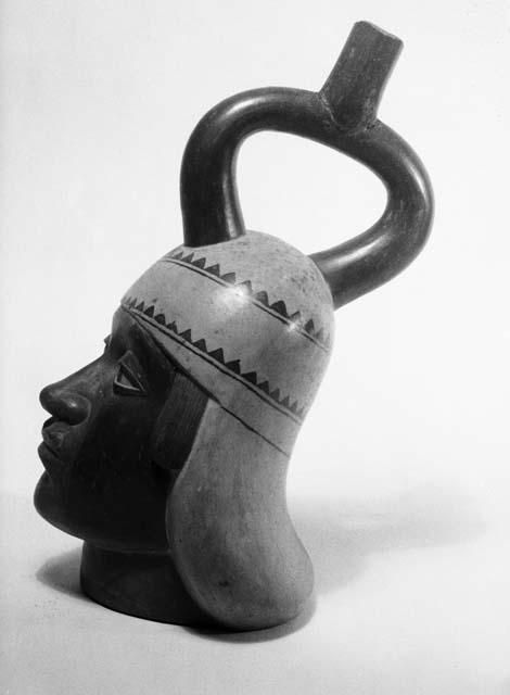 Red and white stirrup pot in form of human head, profile view