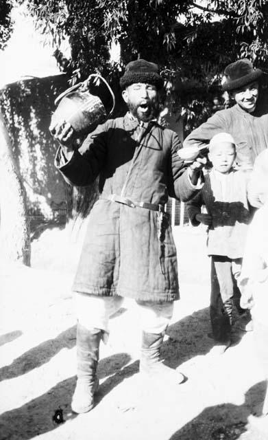 Chantos drinking SuiTing, man and boy standing in background, with jug