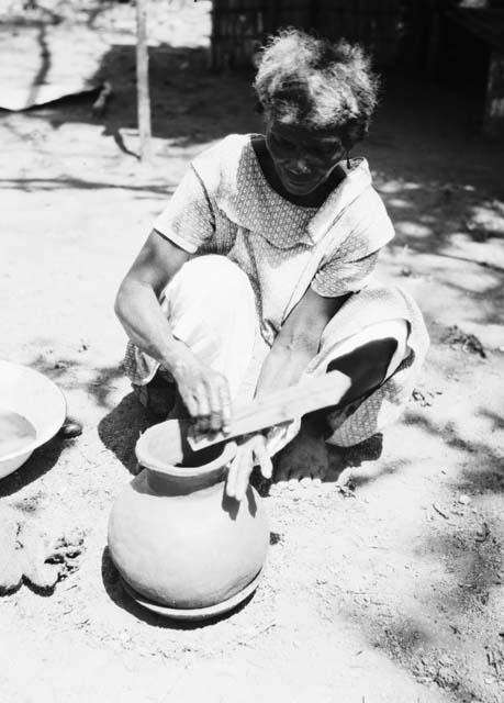 Pottery making, smoothing pottery after adding clay roll