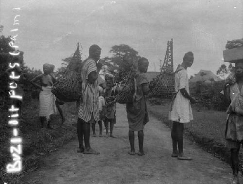 Men carrying pots in palm backpacks