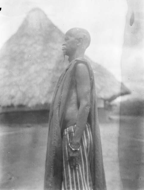 Elderly man, profile view in front of hut