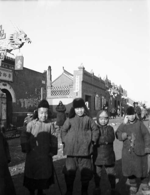 Children standing below elaborate sign with carved dragon's head