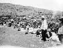 Several people sitting on the ground searing sheep