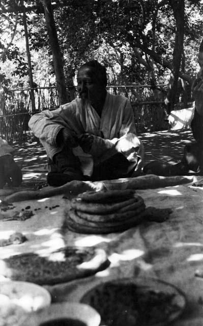 Man sitting in front of pieces of round bread and other food, Grape Valley near